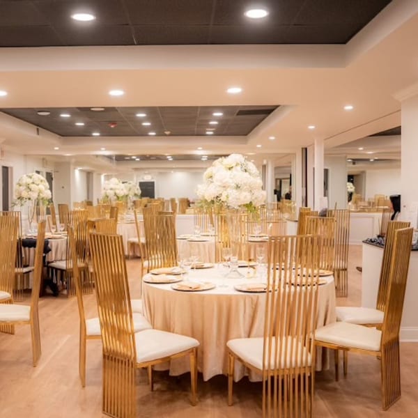 Elegant dining room at The Social on Morton with round tables, gold chairs, and white floral centerpieces.